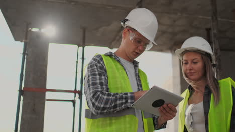 Construction-worker-and-engineer-talking-at-construction-site-site.-Workers-in-helmets-at-building-area.-Portrait-of-construction-engineers-working-on-building-site.-concept-of-modern-construction